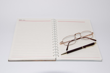 Notebook  pen and glasses isolated on white backgroundの写真素材