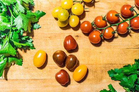 cutting board with parsley and red and yellow cherry tomatoesのeditorial素材