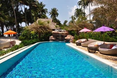 Sunbeds with colorful umbrellas beside a poolのeditorial素材