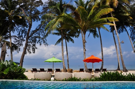 Sunbeds with colorful umbrellas beside a pool overlooking the seaのeditorial素材