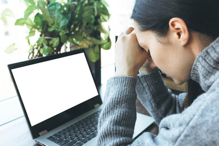 Exhausted caucasian student working on laptop, suffering from headache or migraine. Tired male employee and computer with blank screen. Mockupの写真素材