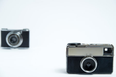 Two classic, retro point-and-shoot cameras positioned on a clean white background. Old-fashioned photographic equipmentの写真素材