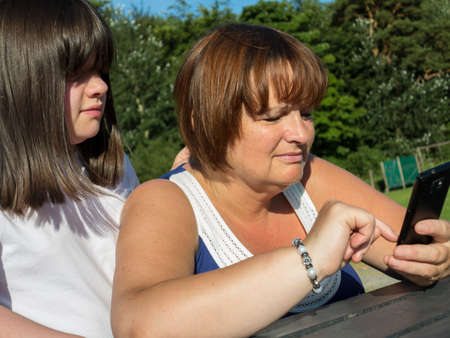 daughter watching her mature mother using a phoneの写真素材