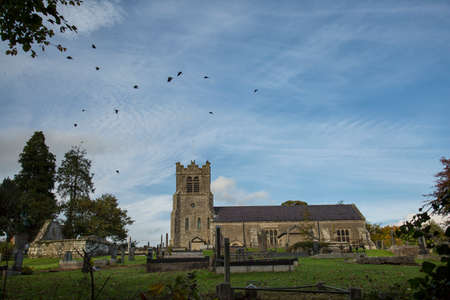 a church and grave yard with crows in flightの写真素材