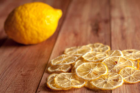 Healthy snack. Homemade dehydrated lemon chips and fresh lemon on a rustic wooden backgroundの写真素材