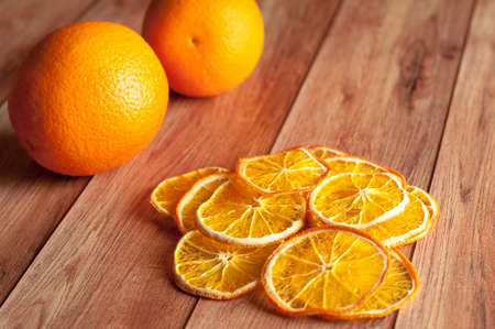 Healthy snack. Homemade dehydrated orange chips and fresh orange on a rustic wooden backgroundの写真素材