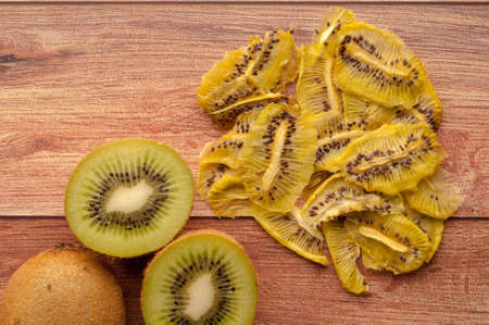Healthy snack. Homemade dehydrated kiwi chips and fresh apples on a rustic wooden backgroundの写真素材