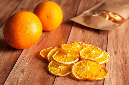 Healthy snack. Homemade dehydrated orange chips and fresh orange on a rustic wooden backgroundの写真素材