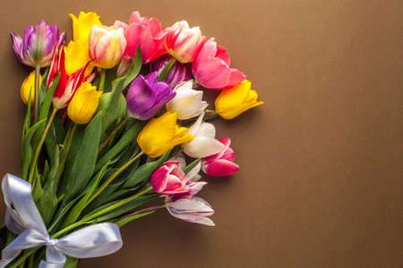 bright spring bouquet of multi-colored tulips on a brown backgroundの写真素材