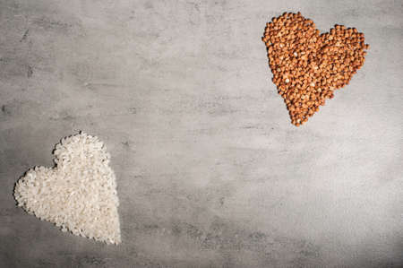 heart of rice groats and heart of buckwheat on a gray background.Copy space