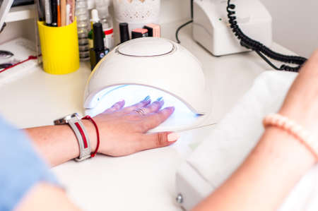 Manicurist work on a woman client hands, make her nails look beautiful.の写真素材