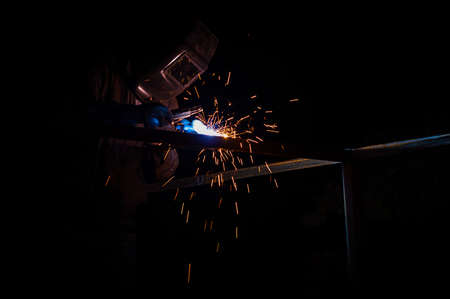 Welder welds a metal garage at nightの写真素材