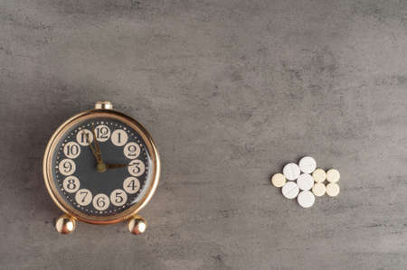 Clock with pills on a gray backgroundの写真素材