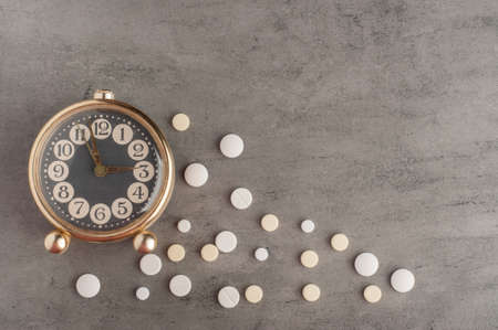 Clock with pills on a gray backgroundの写真素材