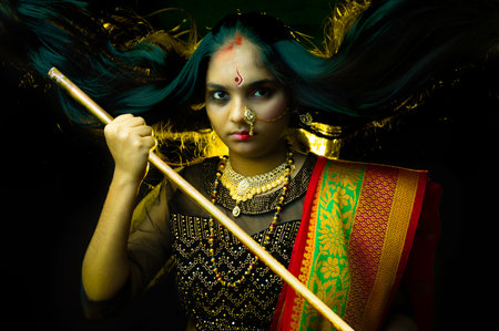 Beautiful Indian girl portrait with a sword, on black backgroundの写真素材
