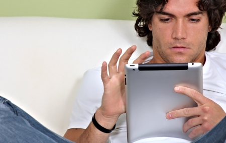 Portrait of an attractive young man using a tablet computer relaxed on bed Portrait of an attractive young man using a tablet computer relaxed on bed