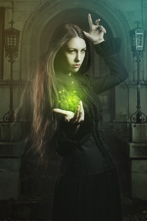 Beautiful young witch casting a spell  . Halloween and fantasy studio shotの写真素材