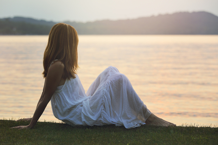 Woman looks at colorful lake waters . Sunset lightの写真素材