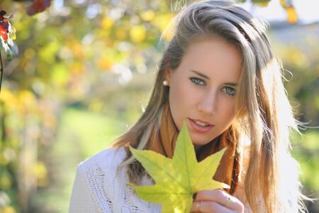Beautiful young woman with autumn leaf  . Seasonal portraitの写真素材