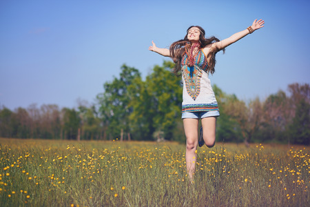 Happy and smiling hippie woman jumps in a summer field . Vintage photo effect