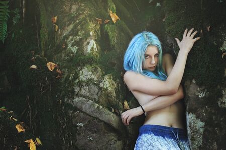 Beautiful woman with cyan hair in dark forest. Fantasy and surrealの写真素材