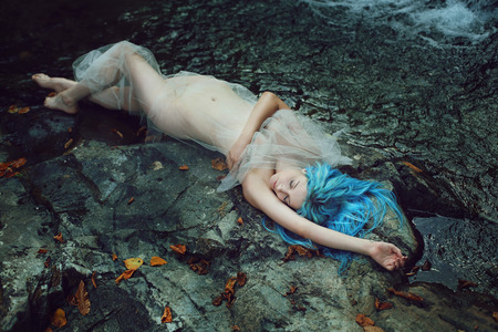 Beautiful river nymph sleeping on the stones . Fantasy and mythの写真素材