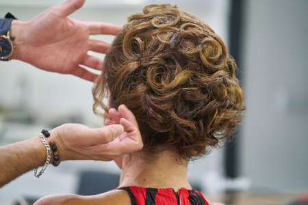 Barber designing good hairstyle of beautiful lady model in the saloon