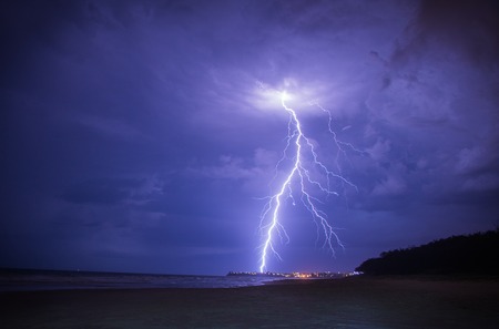 Lightning on a stormy summers night, with city lights in the distance.の写真素材
