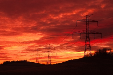 Transmission towers on the hills at red sunsetの写真素材