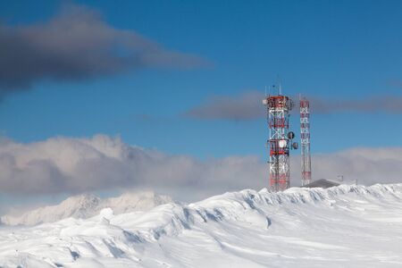 Communication antenna tower and satellite dishes against blue sky.の写真素材