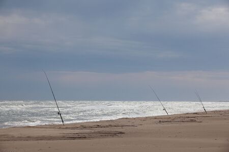 Three fishing rods on an empty beach.の写真素材