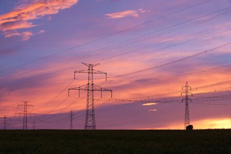 Transmission towers on the hills at red sunset