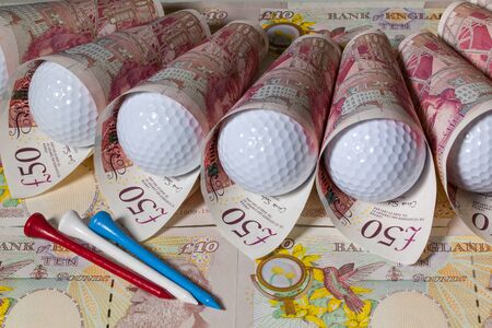 Different British  pounds and white golf ballsの写真素材