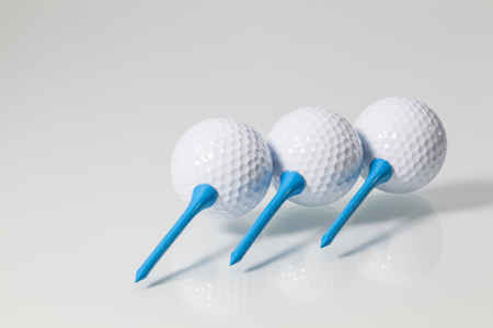 White golf balls and blue tees on a glass tableの写真素材