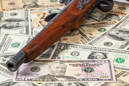 Old gun and dollar bills on the tableの写真素材