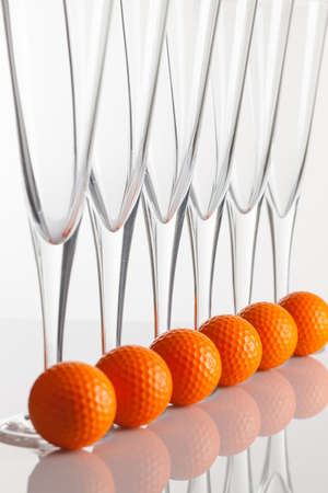 Glasses of champagne and golf equipments on a glass tableの写真素材