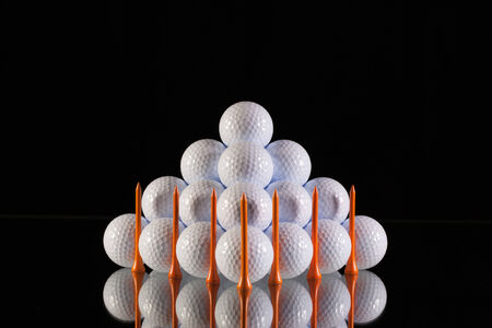 Pyramid of golf balls on a black backgroundの写真素材
