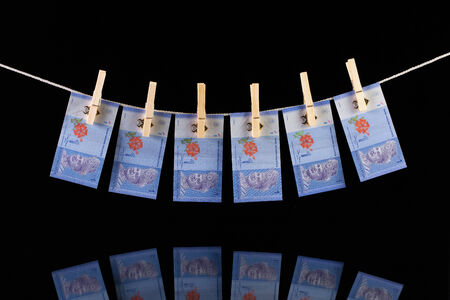 Malaysia Ringgit banknotes hanging from a clothesline and reflecting in the glass