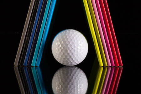 Twelve different colors diaries and golf ball on a glass deskの写真素材