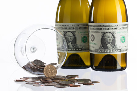 Empty bottles of wine from the label of dollar bill on a glass tableの写真素材