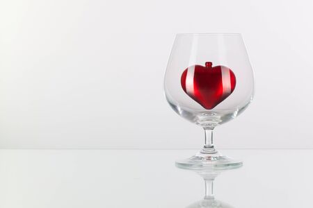 Red heart inside a glass of cognac on a glass plateの写真素材