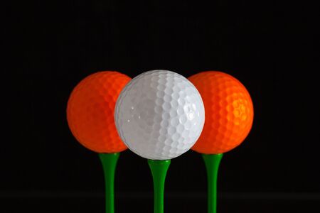 Golf balls and green wooden tees on a black backgroundの写真素材