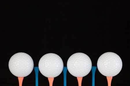 Golf balls and wooden tees on a black background