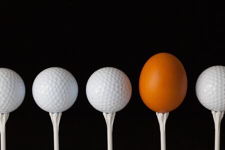 Golf balls and egg on a black glass tableの写真素材