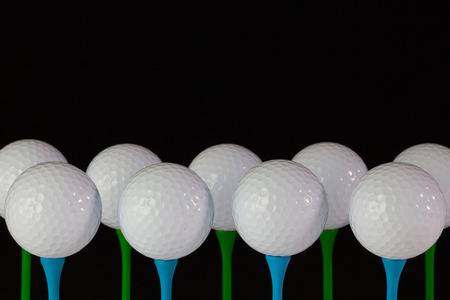 White golf balls on a blue and green wooden teesの写真素材