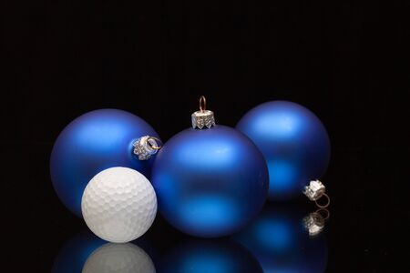 Blue Christmas decoration a golf balls on a black glass deskの写真素材