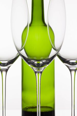 Three empty glasses of wine and green bottle on the white backgroundの写真素材