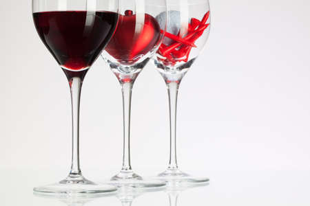 Wine glasses with red wine, heart and golf ball on white tableの写真素材