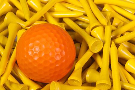 Orange  golf ball lying between yellow wooden golf teesの写真素材
