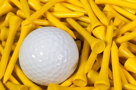 White golf ball lying between yellow wooden golf teesの写真素材